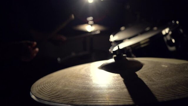 Musician drummer playing hitting drums and cymbals, drumstick close-up view.