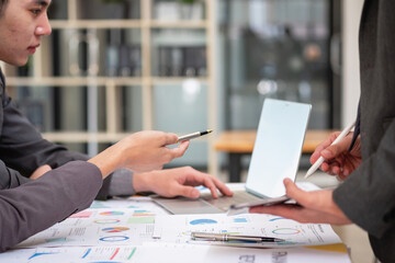 Asian business team consists of marketing staff. accountant and financial officer Help each other analyze company profits using tablets. calculator Laptop computers, graph paper, and corporate pens.