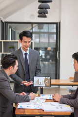 Asian business team consists of marketing staff. accountant and financial officer Help each other analyze company profits using tablets. calculator Laptop computers, graph paper, and corporate pens.