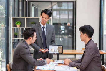 Asian business team consists of marketing staff. accountant and financial officer Help each other analyze company profits using tablets. calculator Laptop computers, graph paper, and corporate pens.