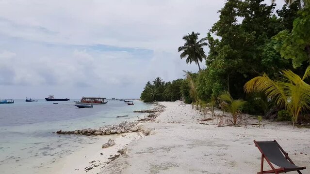 Beautiful view of Indian Ocean coastline with parked boats at sunset. Maldives.