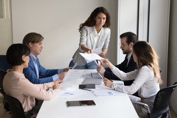 Hispanic boss gives contracts for reviewing terms and conditions together with partners or company clients gathered in conference room during formal meeting in office. Agreement discussion at briefing