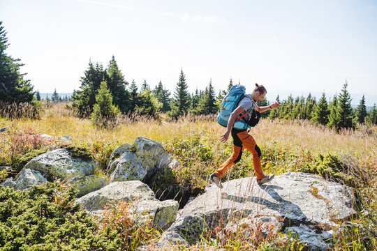 Overcoming an obstacle in a hike, a heavy backpack on your back, a mountain hike, stones under your feet, a guy tourist walking along the trail, running uphill.