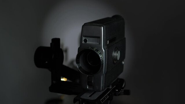 An old movie camera works on an automatic steadicam against the background of a movie projector.