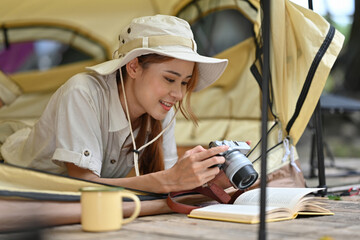 Young female tourist in safari dress Viewing photos on camera while lying inside the tent.