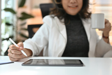 Close up with Senior Mature Business woman using stylus pen and tablet for working while holding a...