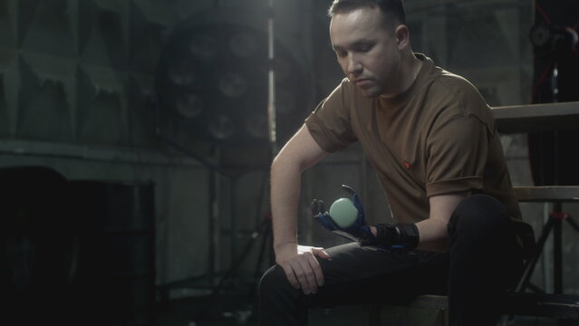 A disabled man with a prosthetic hand raises a dumbbell. Does sports, builds muscle. A fulfilling life with a cybernetic hand prosthesis, inclusiveness - Powered by Adobe