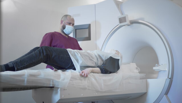The doctor conducts an MRI or PET scan of a patient in a modern clinic. Girl on the bed inside a 3D scan machine. The woman is doing CT scan