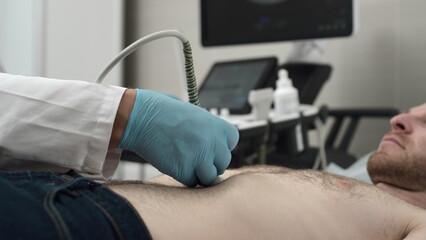 Ultrasound: A doctor checks a man's stomach with an ultrasound machine. Diagnosis of liver and pancreatic diseases. Examination of the body in the clinic office