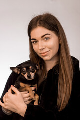 Beautiful brunette girl holding a dog of the ToyTer breed in her arms