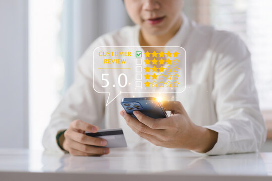 Close-up on a customer hands pressing on a smartphone screen with a gold five-star rating feedback icon after shopping online using a credit card. Client review and customer rating concept