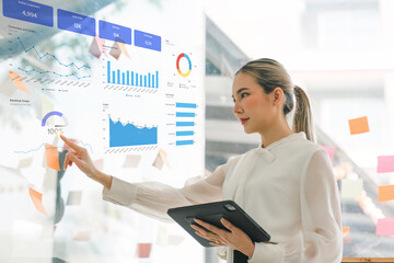 Using a tablet, Businesswoman or accountant is analyzing financial investments, business, and marketing growth on a data graph. The analysis pertains to accounting, economics, and commercial concepts.