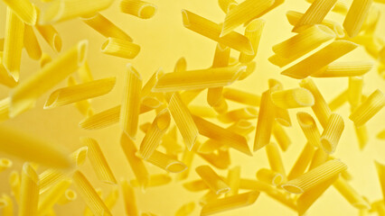 Dry penne pasta flying in the air.