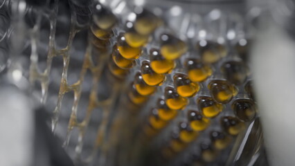 Yellow gel capsules in an automatic machine. Omega 3 or fish oil