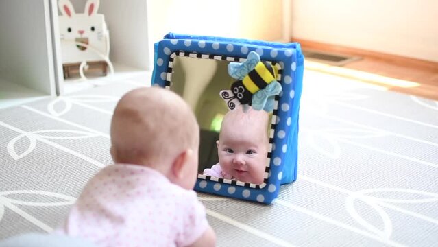 Baby looking in the mirror during tummy time. Baby development stages. 