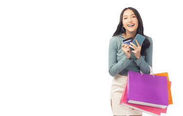Excited asian lady using mobile phone holding credit card carry shopping bags isolated over white...