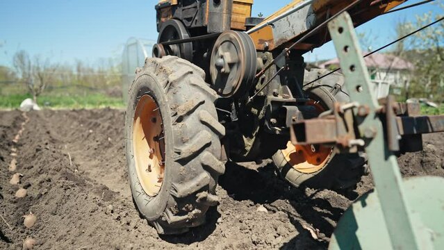Farmer man works, ploughing garden chernozem field with motorized unit motoblock