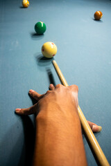Top view of skilled player's hand aiming to make the perfect shot with billiard ball on a sleek blue table