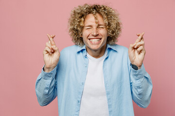 Young caucasian blond man wear blue shirt white t-shirt waiting for special moment, keeping fingers...