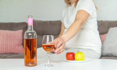 A pregnant woman drinks wine in a glass. Selective focus.