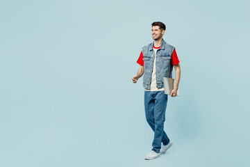 Full body smiling happy young IT man he wears denim vest red t-shirt casual clothes hold closed...