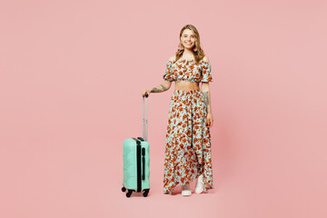 Full body traveler woman wear casual clothes hold suitcase isolated on plain pastel pink color background studio. Tourist travel abroad in free spare time rest getaway Air flight trip journey concept