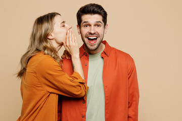 Young couple two friend family man woman wear casual clothes whisper gossip and tell secret behind her hand sharing news together isolated on pastel plain light beige color background studio portrait - obrazy, fototapety, plakaty
