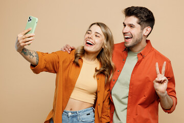 Young couple two friends family man woman wear casual clothes doing selfie shot on mobile cell phone post photo on social network together isolated on pastel plain light beige color background studio.