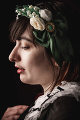 Vertical low-key profile of a young woman in a gothic costume and a ribbon in her hair