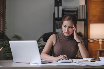 Serious female freelancer working online with accounting documents on modern laptop. Business woman busy working on laptop computer at office.