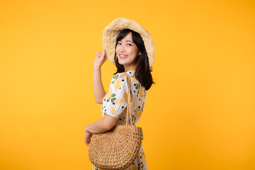 Portrait happy attractive young asian woman with trendy springtime dress, hat, sunglasses fashion and woven bag isolated on yellow background. Summertime sale shopping concept. - obrazy, fototapety, plakaty