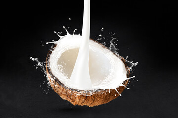 Coconut cut milk pouring front splash isolated on black stone background