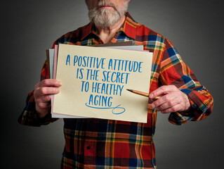 A positive attitude is the secret to healthy aging - inspirational note held by a senior man