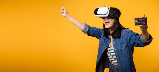 Young asian woman happy success wearing virtual reality headset game entertainment and holding...