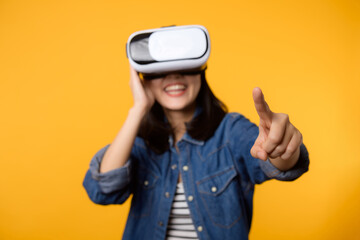 Young asian woman get experienced wearing virtual reality headset game entertainment isolated on yellow background. Winner of cyber future video game concept.