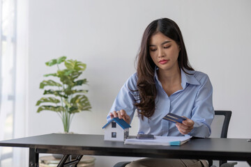 Stressed Asian woman planning to pay loan and calculating credit card debt on the table