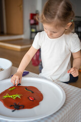 A little girl playing with plasticine and toys insects. Sensory development and experiences, themed activities with children, fine motor skills development