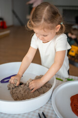 Little girl playing with kinetic sand and toys insect. Sensory development and experiences, themed...