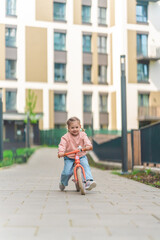 Little girl riding balance bike in the courtyard of the residence in Prague, Europe