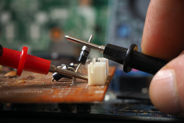 Technician testing electronic component on circuit board. Focused on diode.