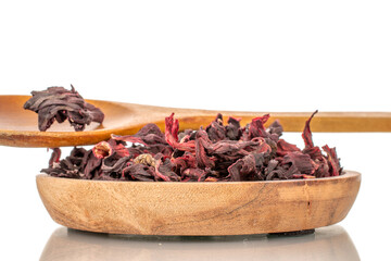 Aromatic Karkade tea in a wooden saucer with a wooden spoon, macro, isolated on white background.