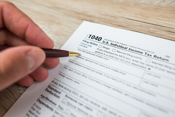 Close-up of a woman's hand filling out an empty tax form in the office.