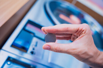 Young woman putting coin in washing machine at laundry