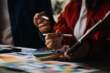 Close up ux developer and ui designer brainstorming about mobile app interface wireframe design on table with customer breif and color code at modern office.Creative digital development agency