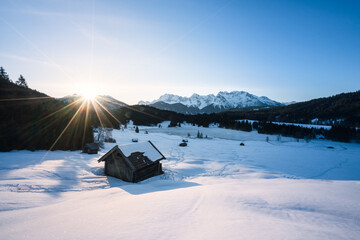 Bayern im Winter mit Hütte und Schnee und Bergen und Sonne als Stern.