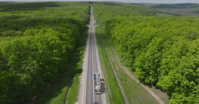 aerial view from drone of moving cistern tank truck on the road in forest