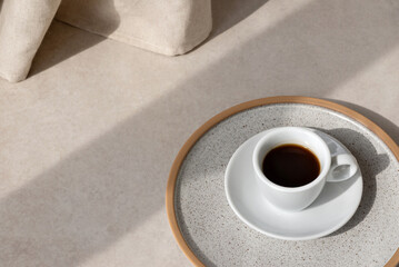 Aesthetic neutral background with coffy cup on beige stone table with sun light shadow, minimalist...