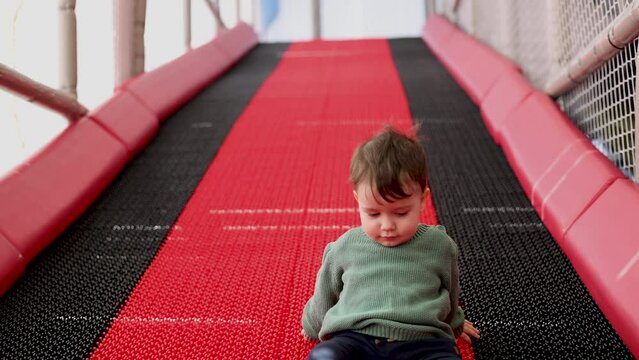 happy baby kid boy child at play center playground using inflatable wheels ring inflatable circle to slide down from artificial hill.joyful kids having fun 4k