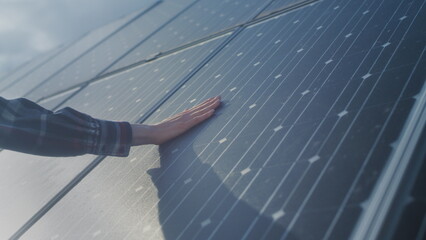 Male engineer touching photovoltaic electric solar panel battery with his hand. Energy Innovation...