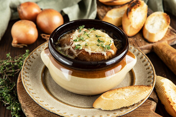 Bowl with French onion soup on wooden table